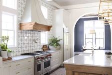a modern Spanish kitchen with a printed tile backsplash, a heavy wooden kitchen island and a white ceiling with beams