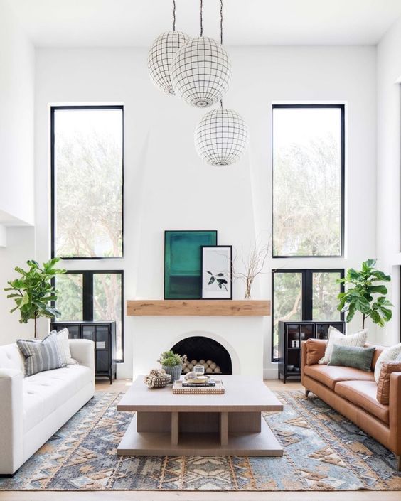 A modern Spanish space with white walls, a faux fireplace, warm colored furniture and bright touches and prints