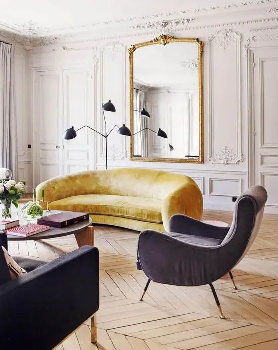 a neutral Parisian living room with molding, a large mirror, colorful curved furntiure and a black floor lamp plus a coffee table