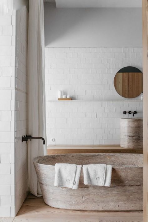 a neutral bathroom with a gorgeous stone bathtub and a matching sink looks refined and very natural