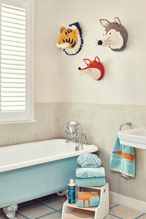 a neutral bathroom with a light blue tub, colorful and fun towels and toy animal heads on the wall