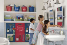a neutral kids’ bathroom with blue and red touches, accessories and a storage board for everyone