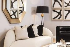 a refined space with a curved white and black sofa, gold touches and bold artworks is an amazing living room