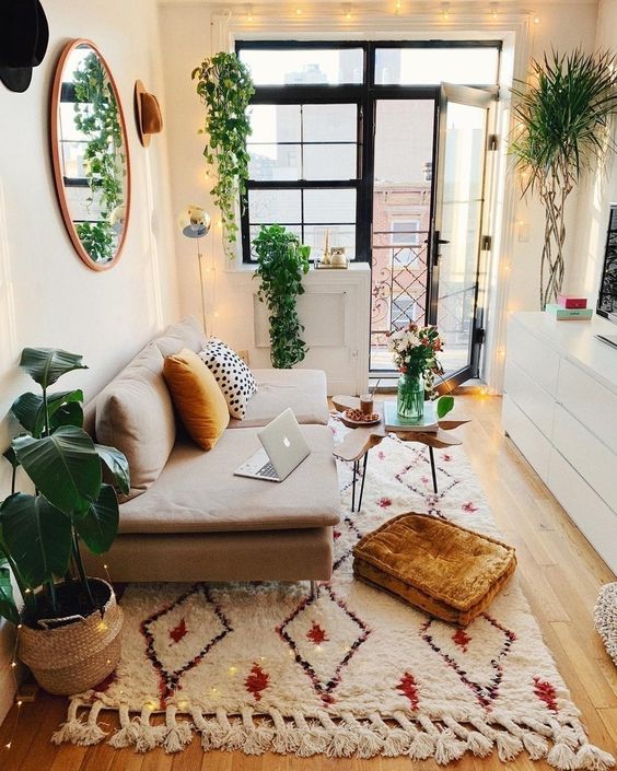 a small boho space with prints, rust touches, lots of potted greenery and string lights all over