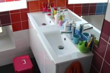 a small modern kids’ bathroom with colorful tiles on the walls and bright stools plus bright accessories