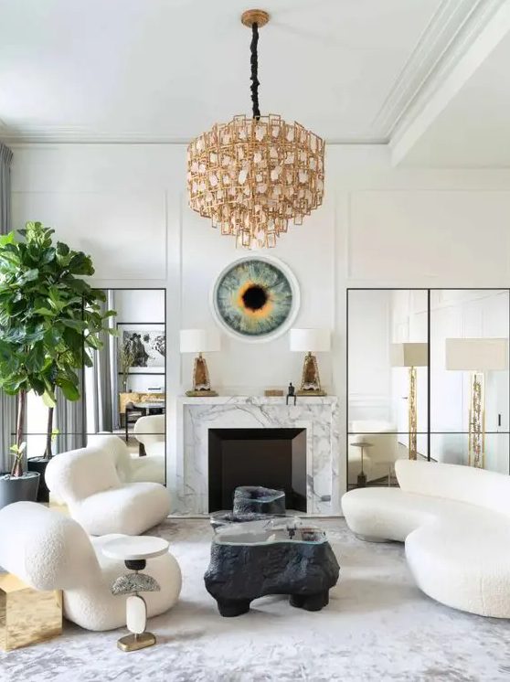 a sophisticated living room with a marble clad fireplace, a curved creamy sofa and matching chairs, black coffee tables, a quirky chandelier