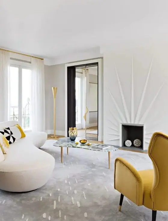an eye-catching living room with a fireplace, a yellow wingback chair, a creamy curved sofa, a curved coffee table and gold touches