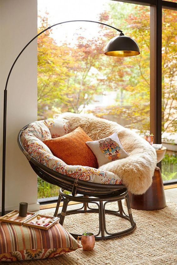 a cool papasan chair of dark sturdy wood, with a colorful futon and pillows to form a cozy reading nook by the window