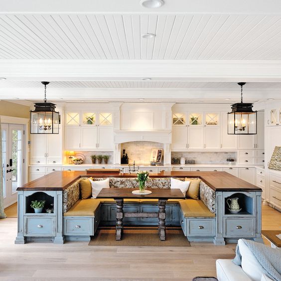 a farmhouse kitchen done in white with a blue kitchen island that includes storage and a seating area