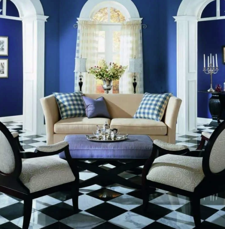 a small living room done in blueberry blue, with a black and white tile floor, various prints and arched windows