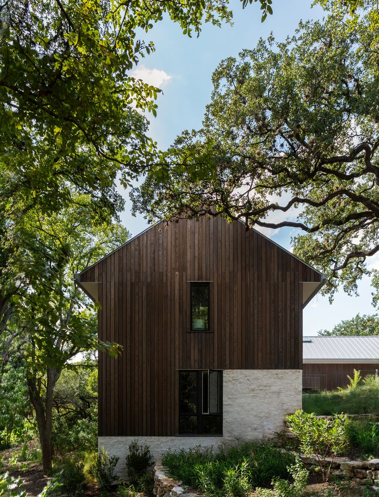 The exterior of the house is clad with weathered wood and has a natural finish