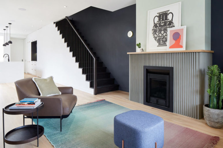 The living room is represented with a grene fireplace, comfy mid-century modenr furniture and a gradient rug