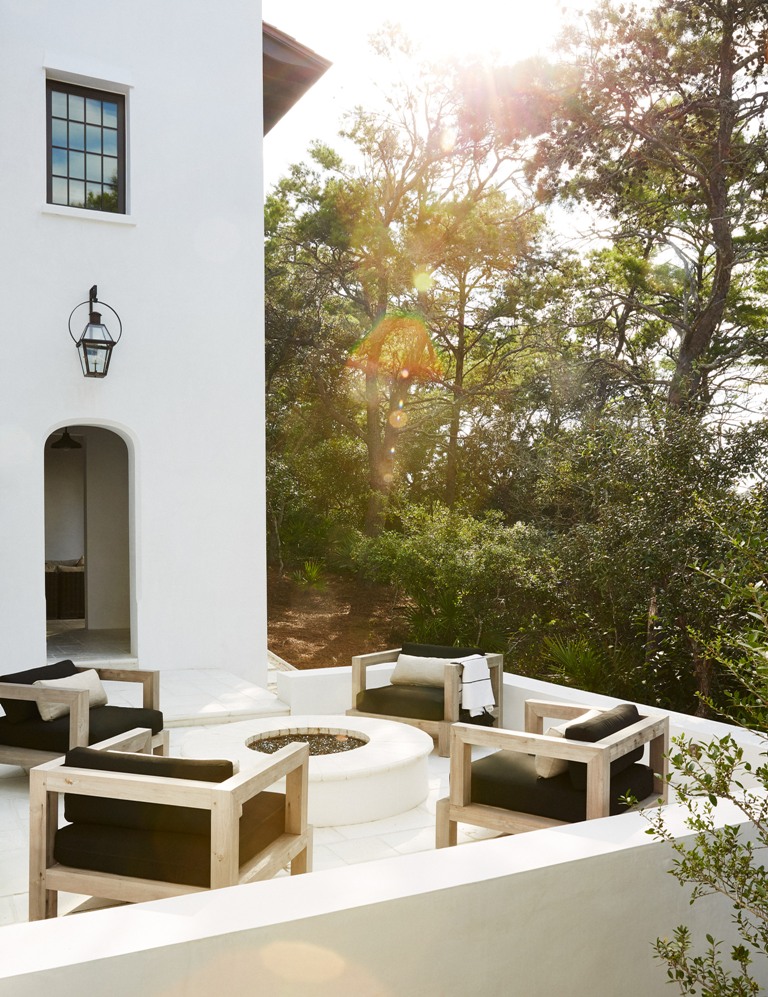 Thhe terrace is perfectly styled with black chairs and a fire pit in the center