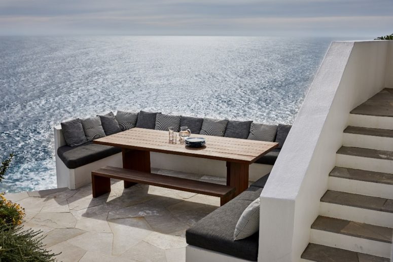 This is a cool outdoor dining space with a built-in bench, a table and amazing views