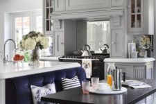 03 an eclectic kitchen with grey furniture, a white kitchen island with a navy seat built-in to compose a dining space