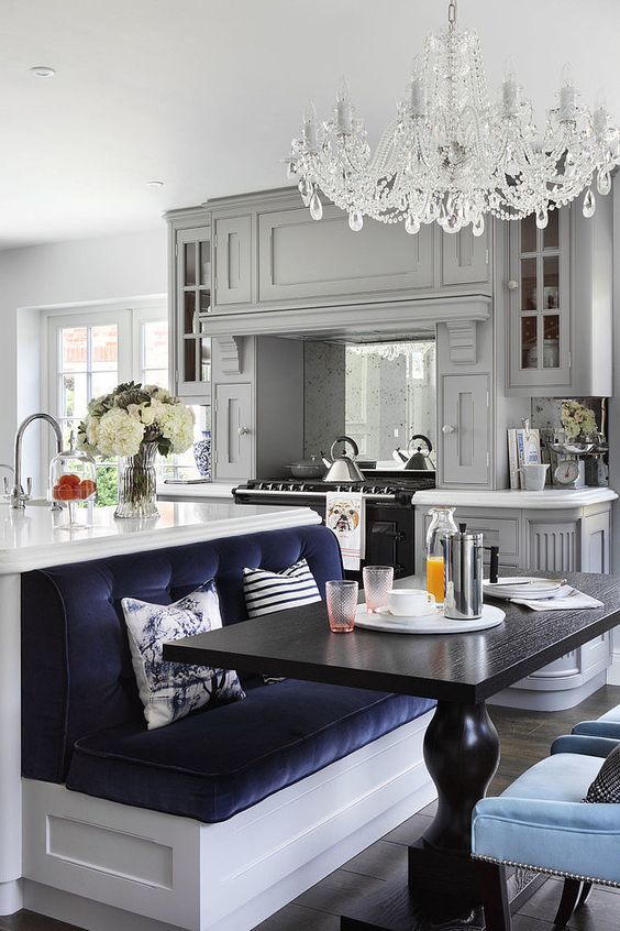 An eclectic kitchen with grey furniture, a white kitchen island with a navy seat built in to compose a dining space