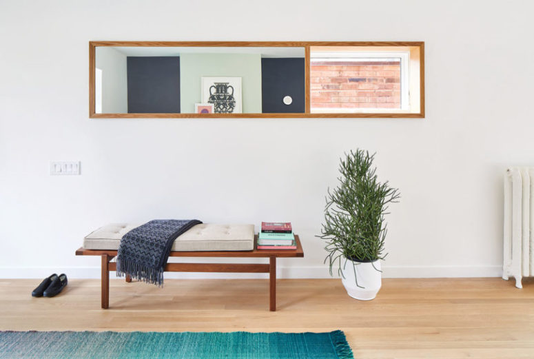 The entryway is clean and simple, with an upholstered bench and a potted plant in a geometric planter