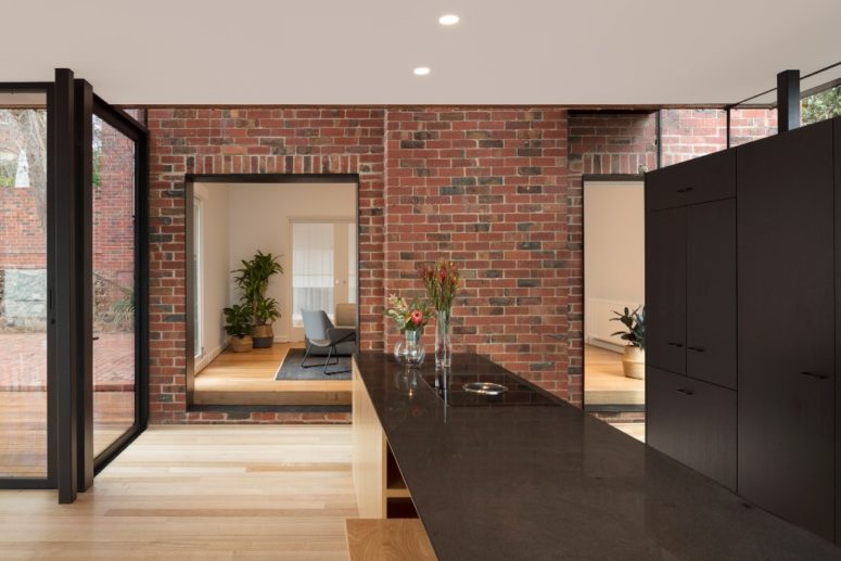 The kitchen is done dark, with chocolate brown cabinets and a kitchen island, a brick wall adds texture