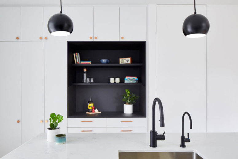 The kitchen is done in white, with wooden knobs and a black niche in the center to make a statement