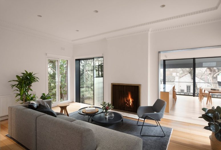 The living room is done with contemporary furniture, a built-in fireplace and potted plants