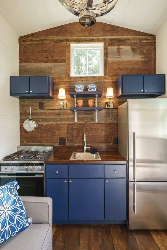 a tiny kitchen with a wooden statement wall, blueberry blue cabinets for a touch of color