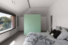 06 The bedroom features white and mint cabinets, a comfy bed and a view through a large window