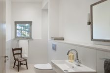 07 The bathroom is neutral, with white tules of various sizes and a window for more light