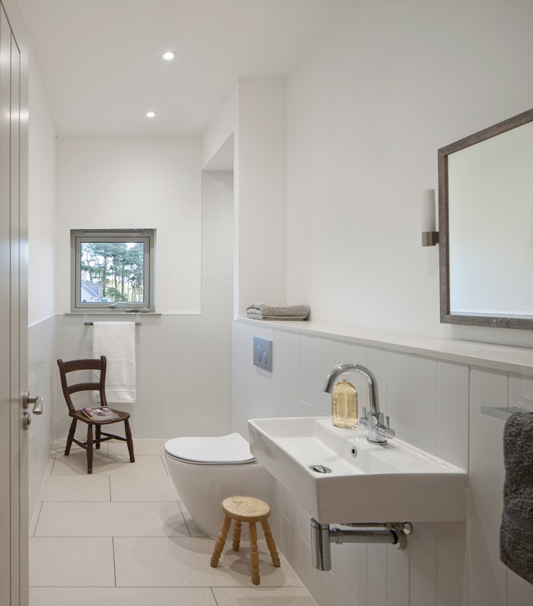 The bathroom is neutral, with white tules of various sizes and a window for more light