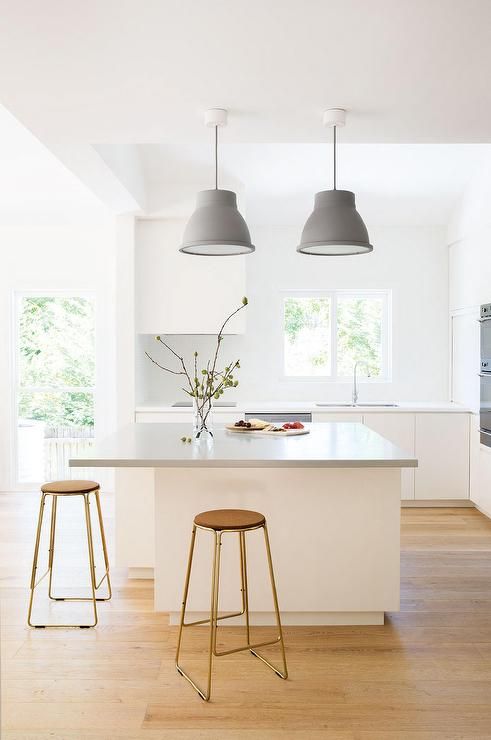A light filled Scandinavian kitchen with a large kitchen island that features a longer countertop for comfortable eating here