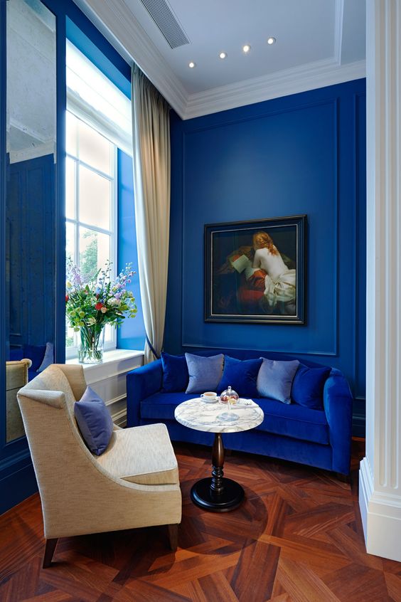 a refined yet tiny living room with blueberry blue walls and a bright blue sofa for a bold touch