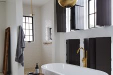 08 The bathroom features lots of blakc shutters, metallic lamps and a chic shower space
