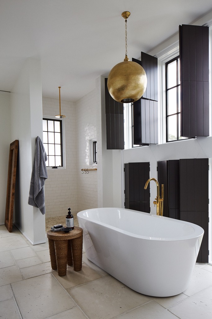 The bathroom features lots of blakc shutters, metallic lamps and a chic shower space