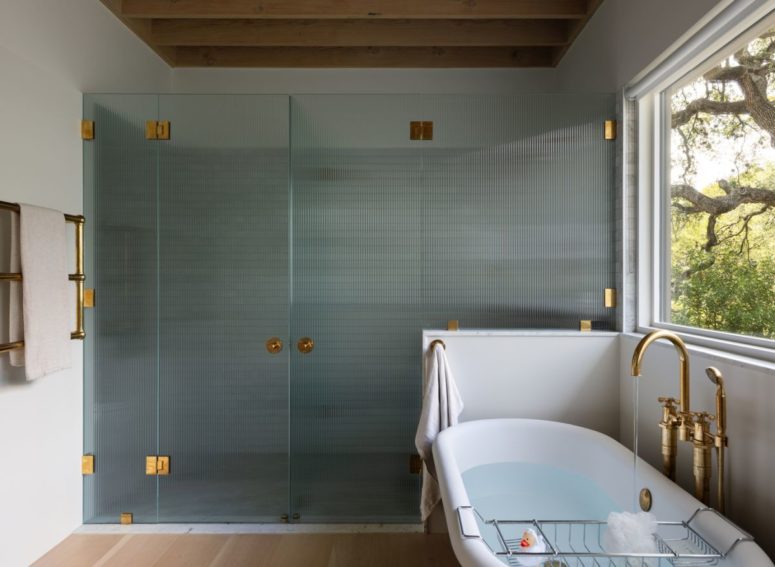 The bathroom has a shower area encased in textured glass with golden metal fixtures
