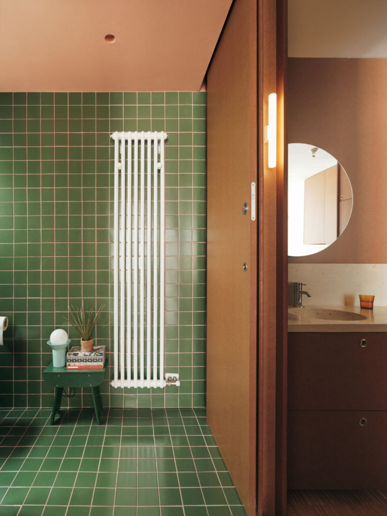 The bathroom is clad with green tiles and highlighted with pink grout for a touch of color
