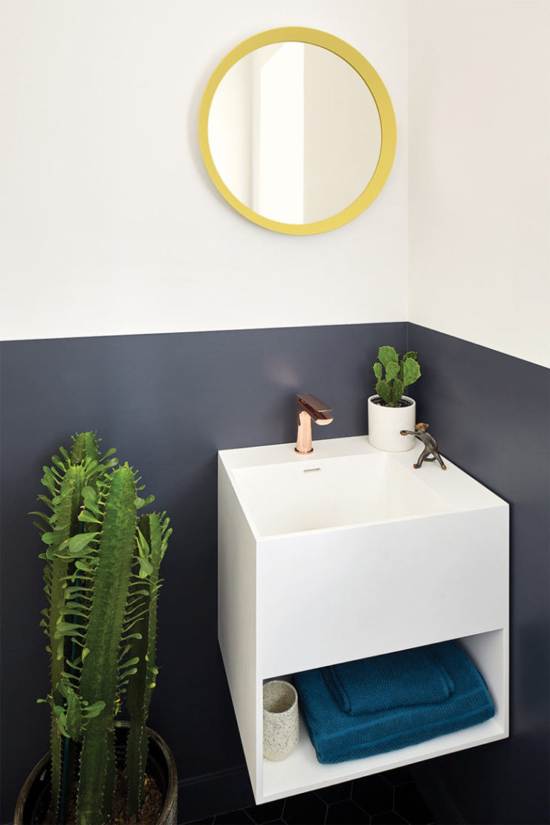 The powder room features color blocking, potted cacti and a floating sink with storage
