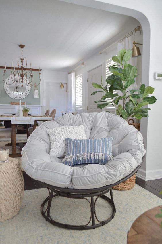 a dark wooden papasan chair with a neutral and pastel futon and pillows for a farmhouse space