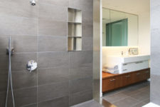 09 The bathroom is contemporary and clean, done with grey tiles and with clean tiles all over