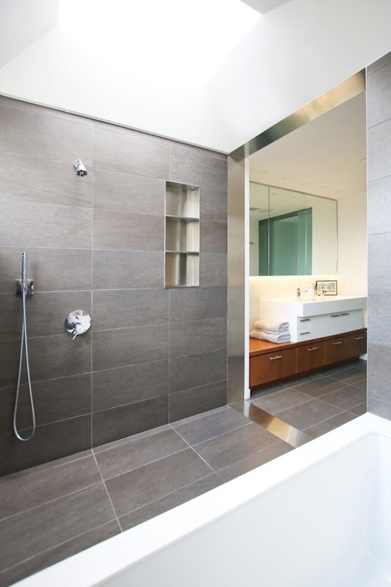 The bathroom is contemporary and clean, done with grey tiles and with clean tiles all over