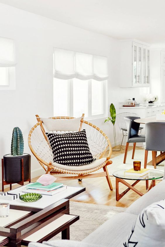 a papasan chair styled in a boho way, with macrame and monochromatic pillows for a boho space