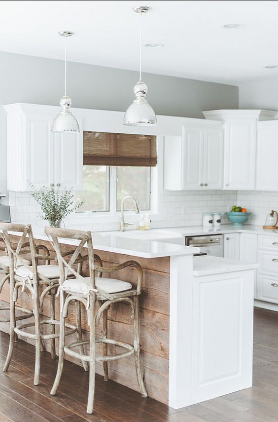 a white farmhouse kitchen with a kitchen island that features a raised countertop for eating here