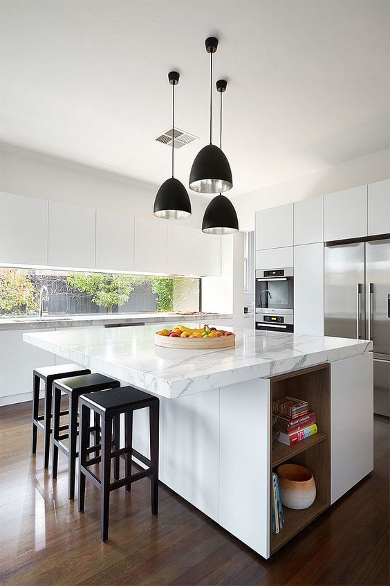 a contemporary kitchen done in white, with an oversized kitchen island that features storage and a countertop for eating at the same time