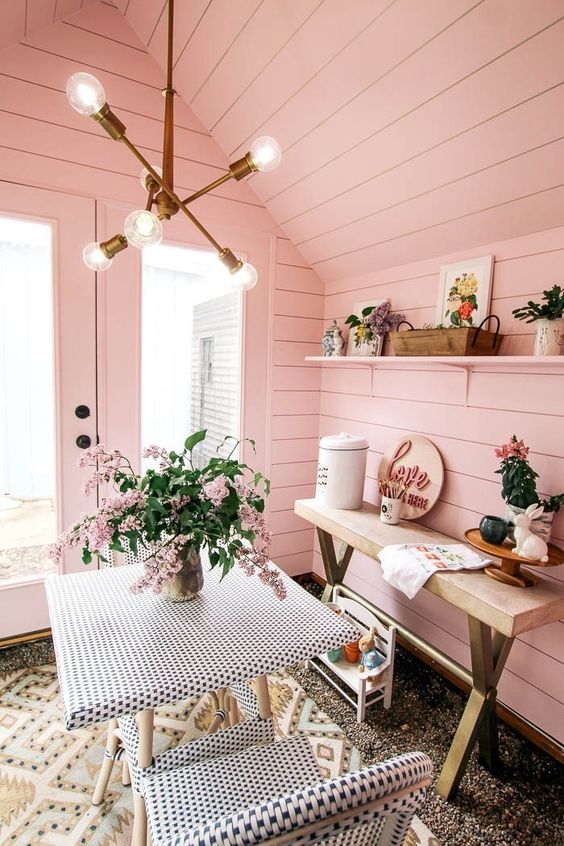a cozy and cute she shed with a small dining space, a console table and some toys for kids to spend time here