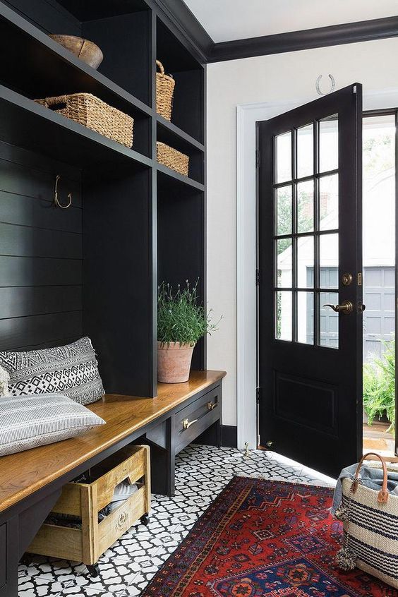 a small farmhouse entryway with onyx-colored furniture and a door that contrast white and red touches all over