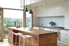 11 a modern kitchen in white, with a wooden kitchen island that is good both for eating and cooking here
