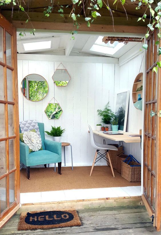 a small garden shed with a reading nook and a small workspace plus an arrangement of mirrors to enlarger the space