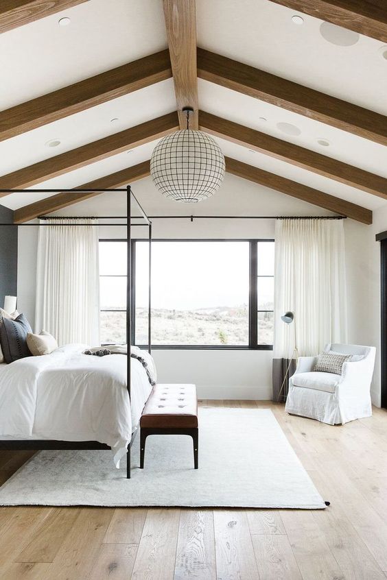 a neutral farmhouse bedroom with wooden beams on the ceiling and a statement sphere lamp