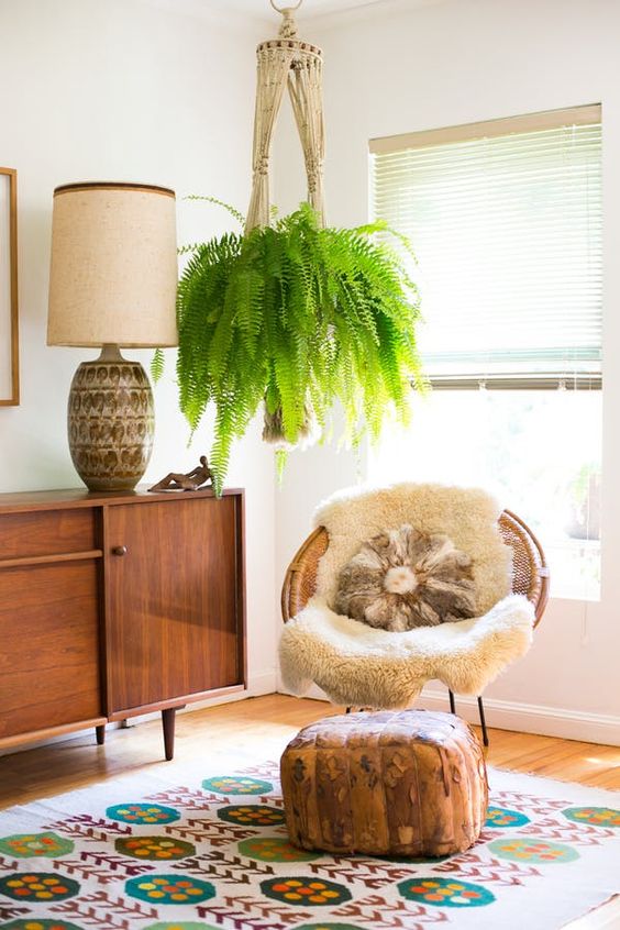 a woven papasan chair with a faux fur rug and a pillow paired with a faux leather ottoman for a boho space