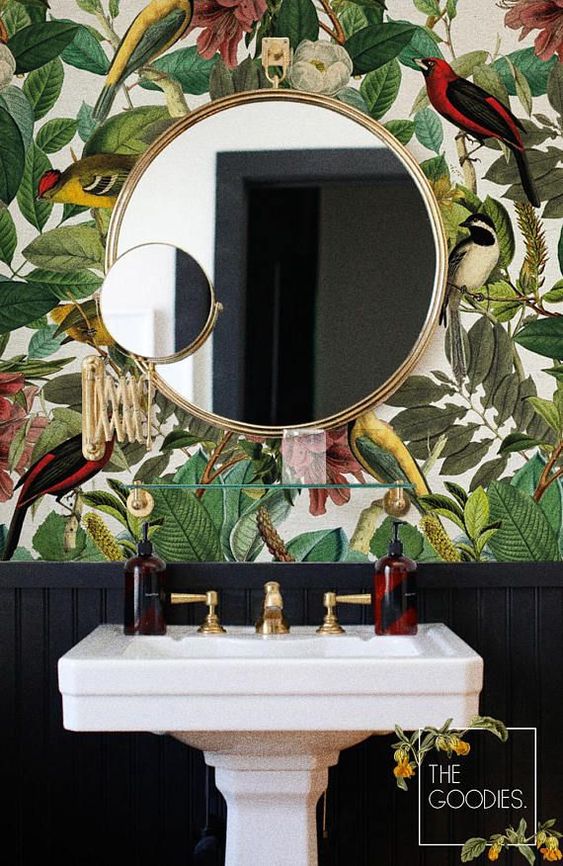 a moody powder room with bright flora and fauna wallpaper and some gilded touches for a bold look