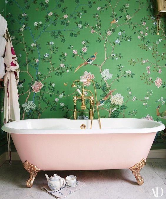 a chic girlish bathroom with flora and fauna wallpaper, a pink clawfoot tub and gold fixtures looks amazing