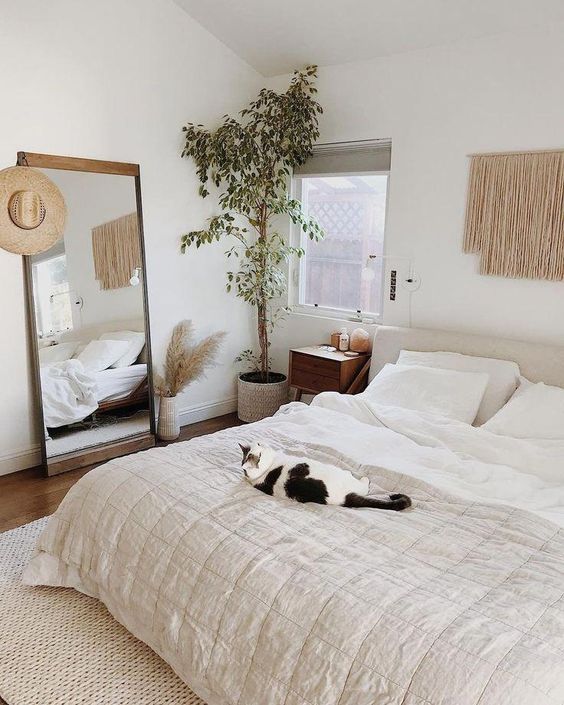 a neutral boho bedrom with a statement potted plant in the corner that makes it fresher and more welcoming